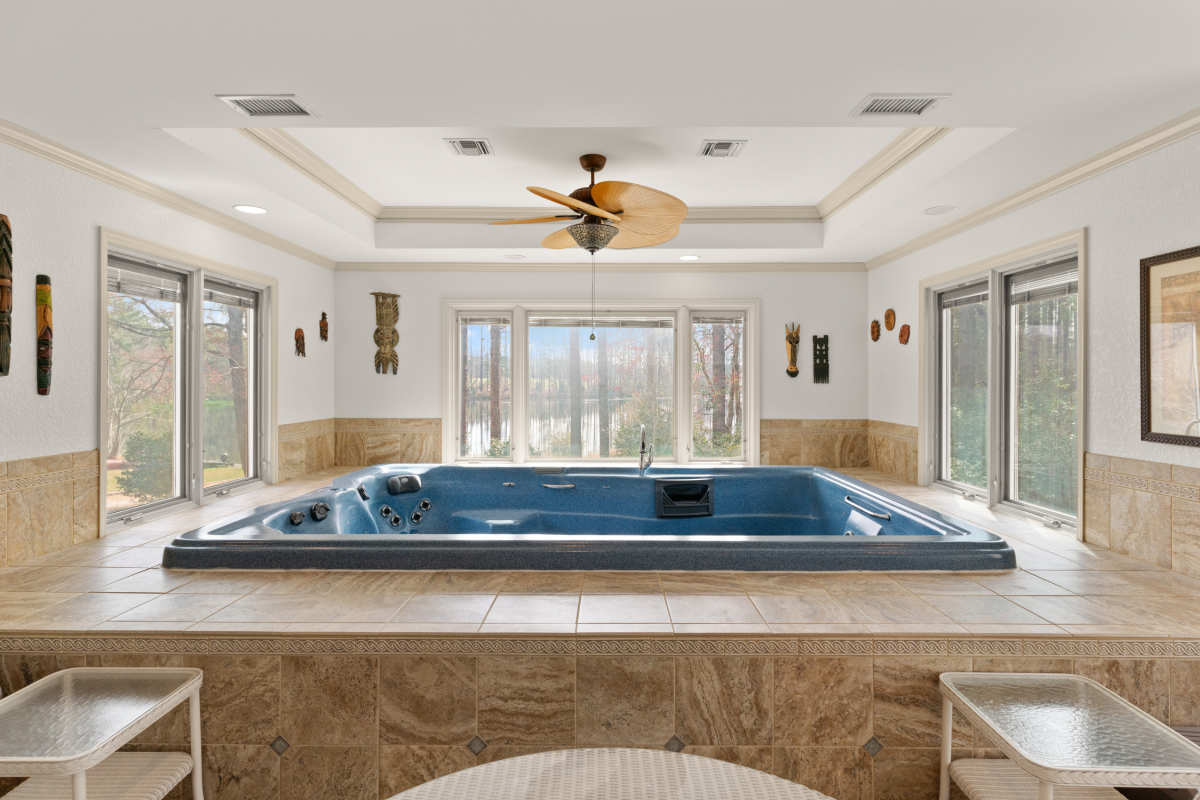 Indoor swim spa with lounge area and panoramic views of the stocked lake