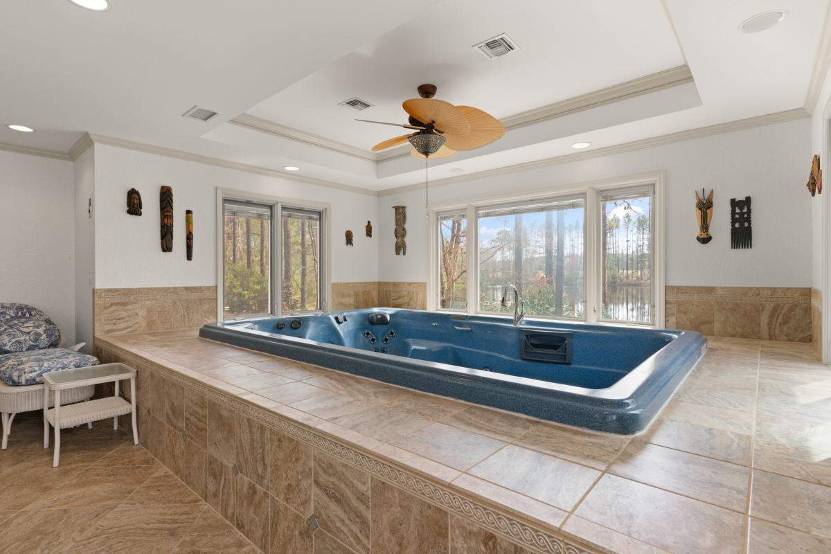 Indoor swim spa with lounge area and panoramic views of the stocked lake